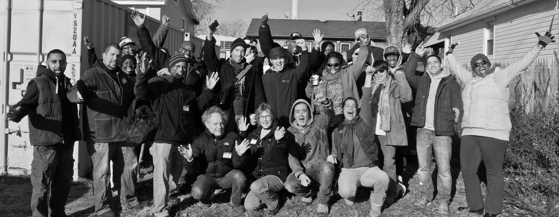 Volunteers smile for a photograph with outstretched arms